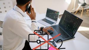 Uomo davanti a due PC mentre parla al cellulare