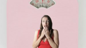 Bilancia in primo piano e donna spaventata