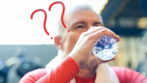 Uomo che beve acqua da una bottiglia di plastica